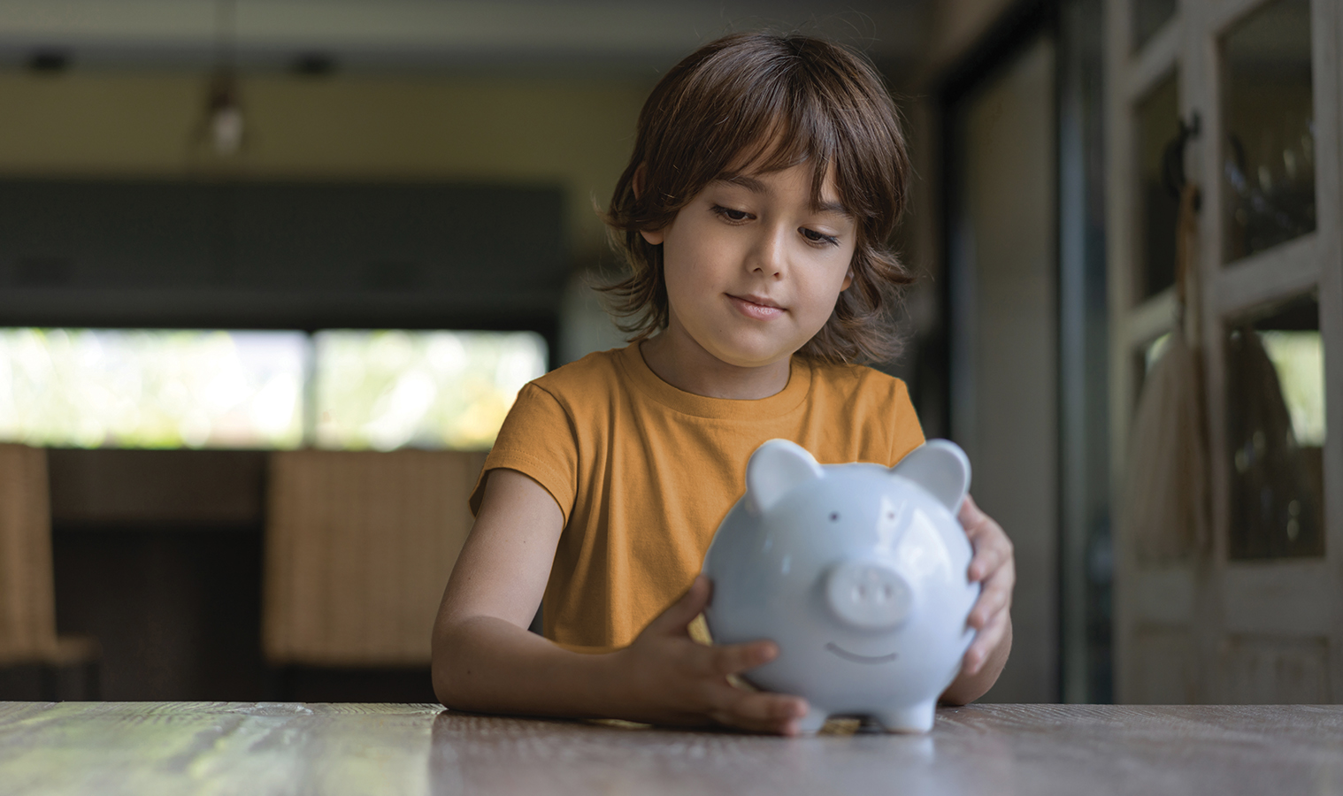 A small child putting money into a piggy bank